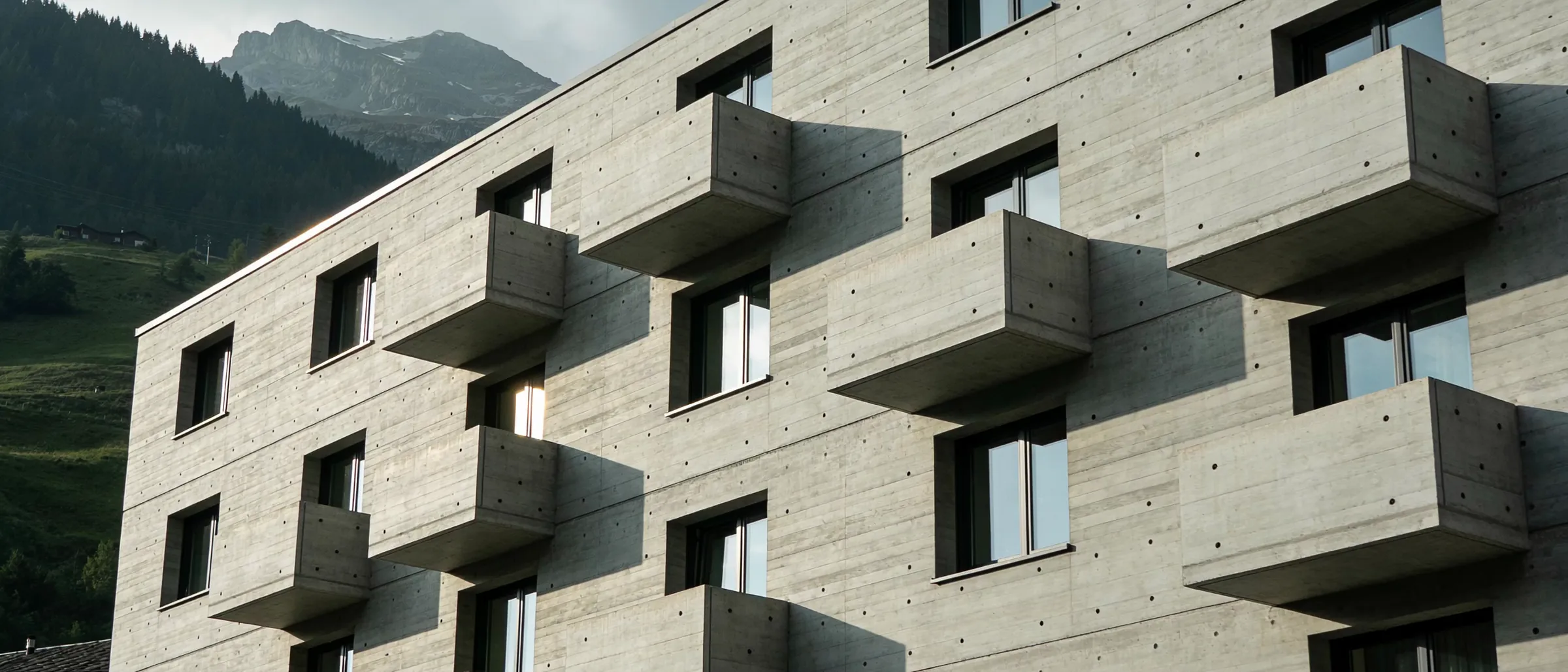 Façade d'immeuble en béton apparent, balcons en porte-à-faux, vallée valaisanne